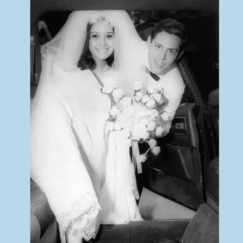 Female bride and male groom exiting a car in a black and white photo.
