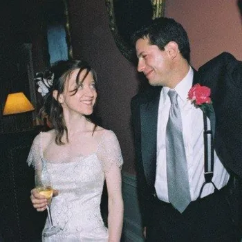 Formally dressed couple smiling at each other with a locked embrace in a hotel or ball room.