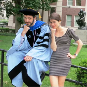 Male in alum robes and female imitating the Columbia "The Thinker" statue pose outside of the Philosophy Hall.