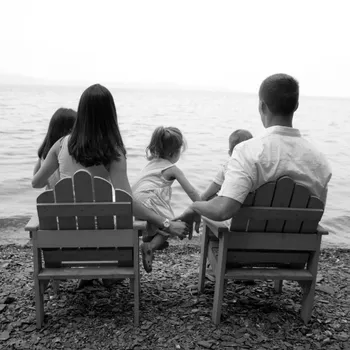 Black and white photo of a family at the beach with their back to the camera.