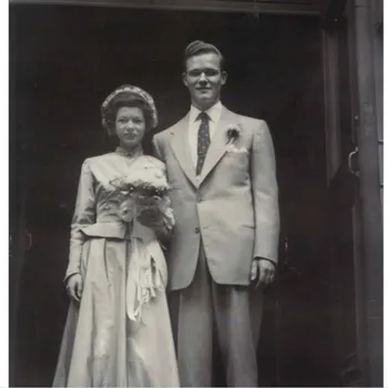 Black and white photo of a formally dressed women on the left and man on the right posing together for a picture.
