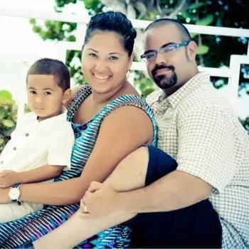 From left to right, young child, adult female, and adult male all in warm embrace.