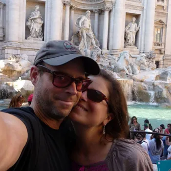 Smiling male with women touching cheeks behind popular monument.