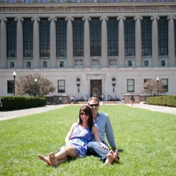 Male and female couple sitting on the grass in front of Butler library