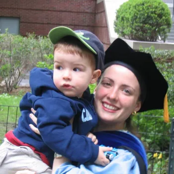 A women with Columbia alum robes holding up her son.