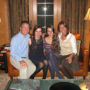 Male and female couple sitting in a den setting with their two teenage daughters. 