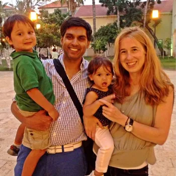 Brightly smiling couple with their two small children in arms.
