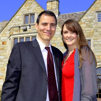 Male and female couple standing in front of a stone building