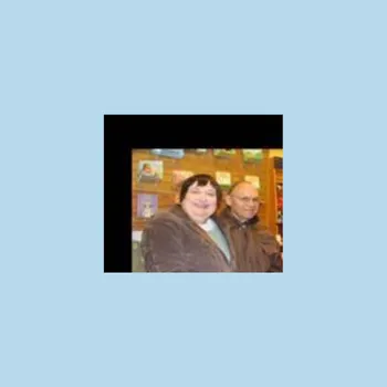 A couple smiling in the midst of a coffee shop with artwork on the walls.
