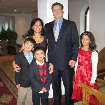 A man, a women, and their three children proudly standing together.