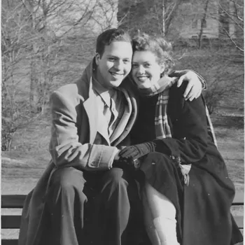 Black and white photo of couple sitting down and hugging in the cold.