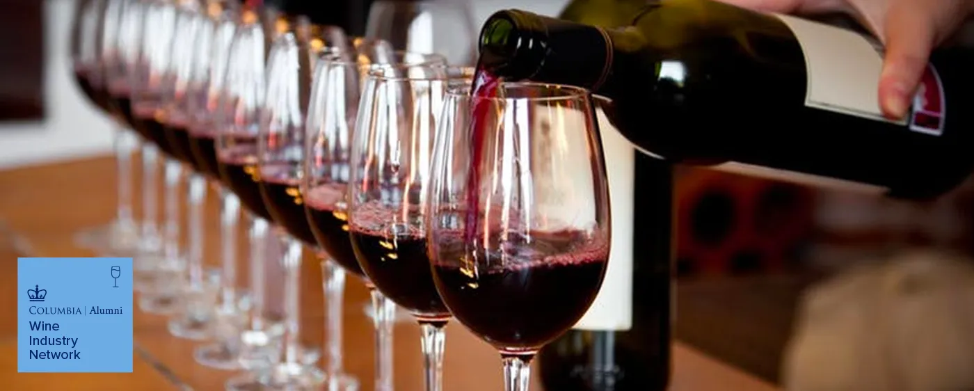 Red wine being poured into a row of glasses, with a Columbia Alumni Wine Industry Network logo overlay.