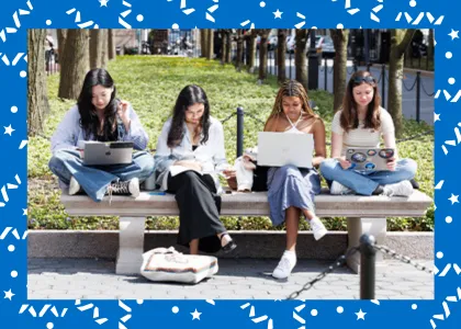Four college students studying on laptops outdoors on campus.