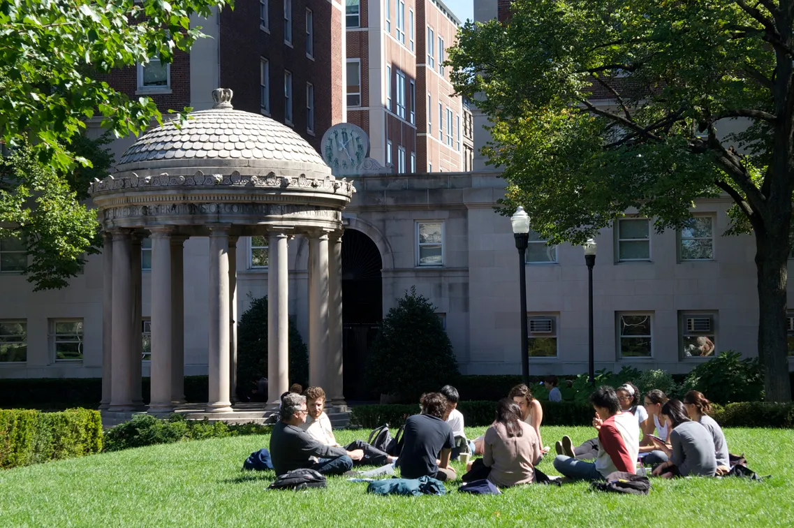 Students sitting on a lawn in front of a domed pavilion on a Columbia University campus, studying together outdoors.