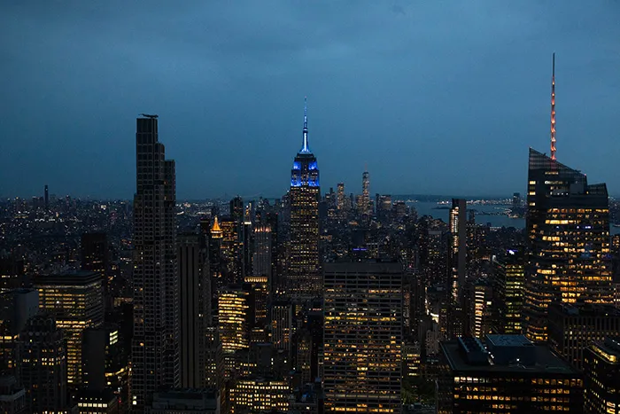 The Empire State Building in the evening, lit with blue lights at the top.