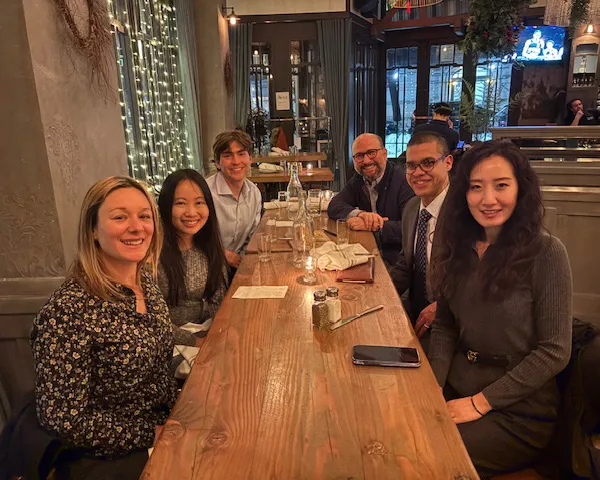 Alumni and students sitting at long tables in a restaurant and dining.
