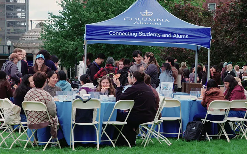 Students sitting at tables in front of Columbia Alumni tent