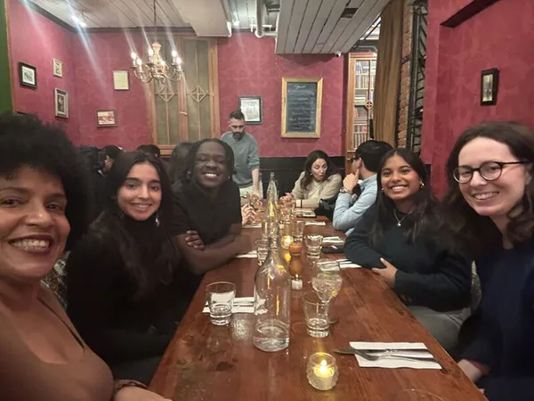 Alumni and students sitting at long tables in a restaurant and dining.