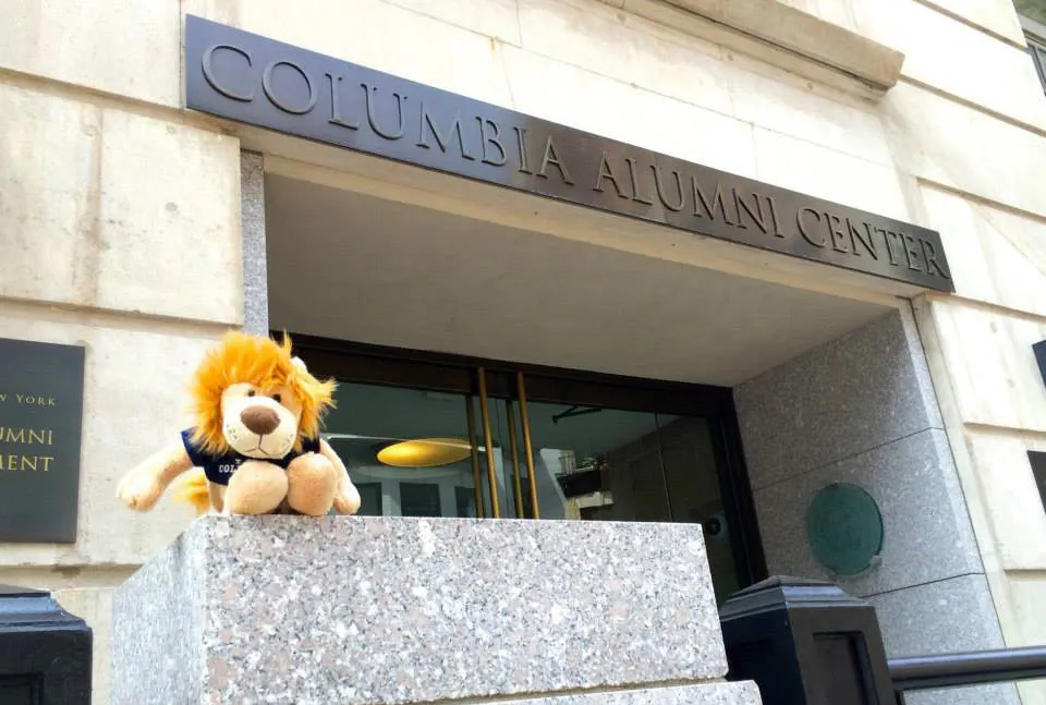 Plush lion toy in front of the Columbia Alumni Center entrance sign.